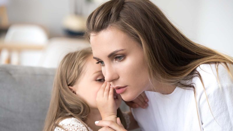 Loving mother listens to child girl whispering in ear telling psychological problem, serious caring mom supporting little daughter share secret, honesty trust understanding in parent and kid relation